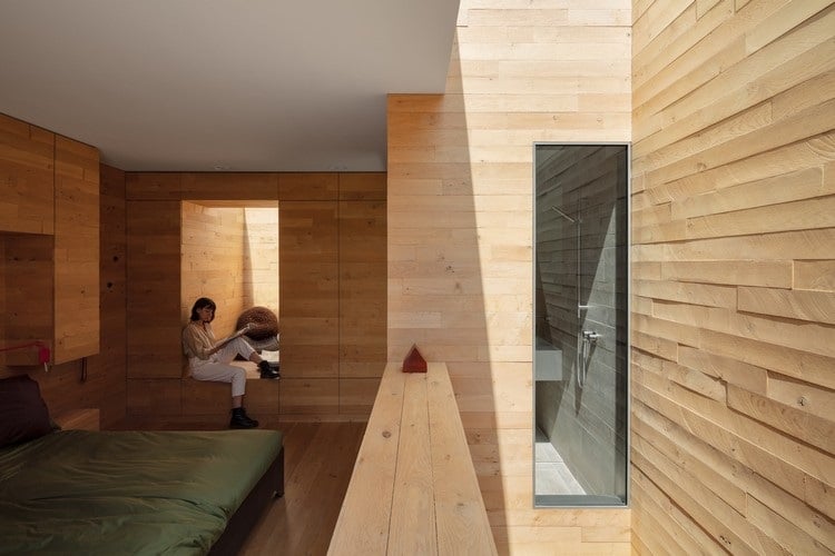 Schlafzimmer mit Holzwänden und Badezimmer mit Keramikfliesen