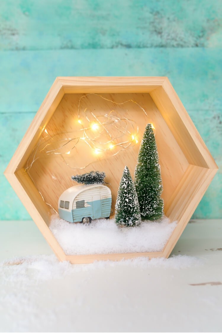 Winterlandschaft basteln in einem sechseckigen Kasten mit Wohnwagen, Lichterkette und Tannenbäumen