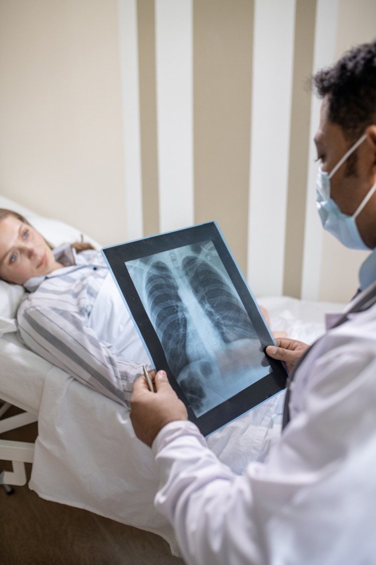 arzt sieht sich röntgenaufnahme der lunge von junger frau mit covid 19