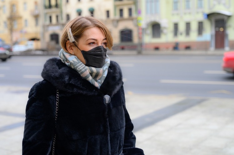 dick angezogene junge frau mit schutzmaske auf der straße während der pandemie von covid 19