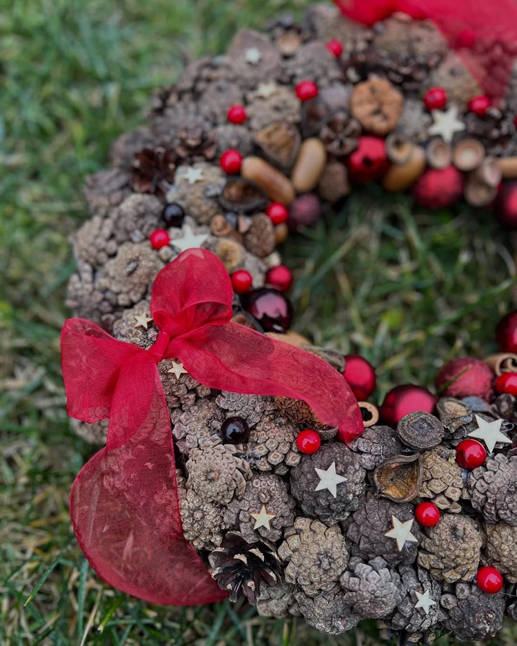 diy weihnachtskranz aus tannenzapfenn und roten schleifen