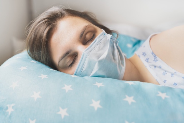 frau mit schutzmaske beim schlafen während der covid 19 pandemie