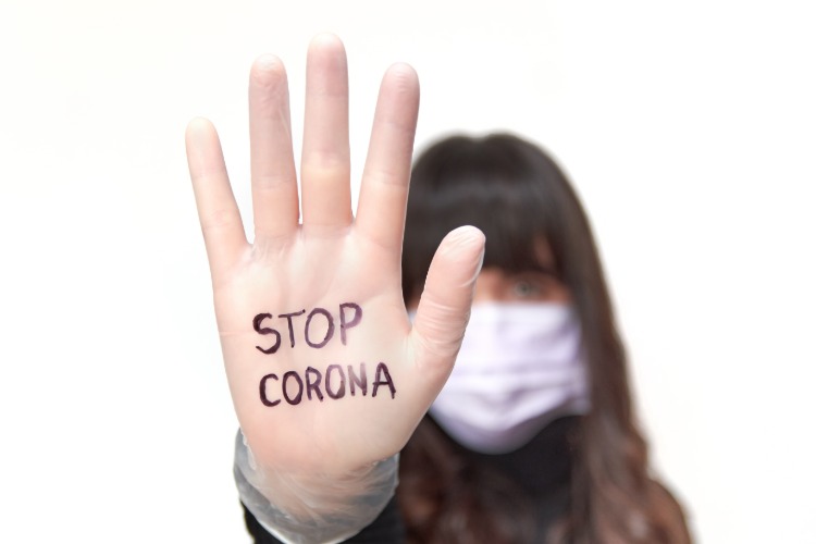 frau mit schutzmaske und aufschrift stop coronavirus auf der hand