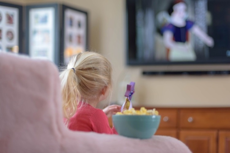 kleines mädchen beim fernsehen mit popcorn zu hause