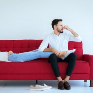 mann und frau auf dem sofa sitzend vom fußgeruch gestört