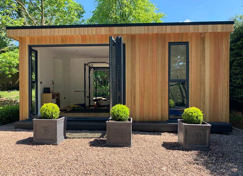 modernes Gartenhaus mit Falttüren und Holzfassade