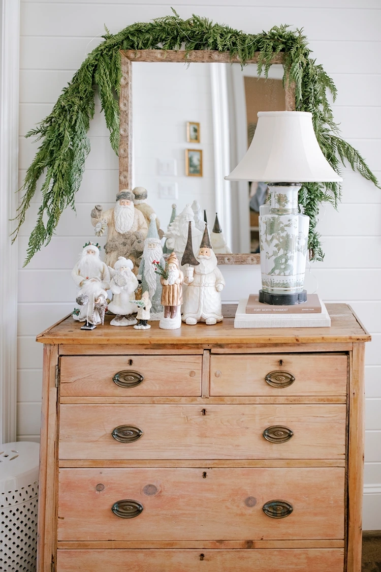 schlichte girlande aus zypressenzweigen und nostalgische weihnachtsfiguren