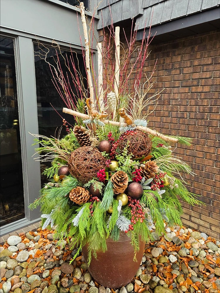 winterliches gesteck für den garten mit immergrünen zweigen und zapfen