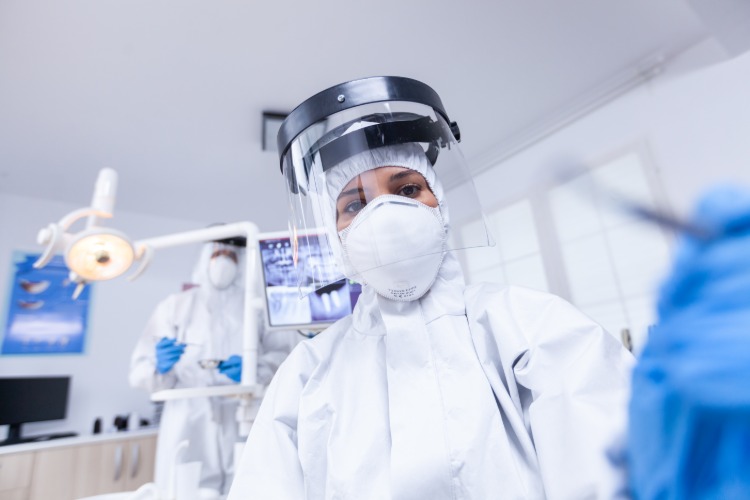 zahnärztin trägt schutzvisier während behandlung von patienten aufgrund von covid 19 pandemie