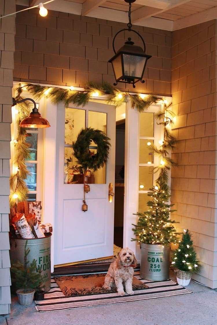 Haustür weihnachtlich dekorieren Girlande mit Licherkette und Eimer mit Holzscheiten und Mini Bäumchen