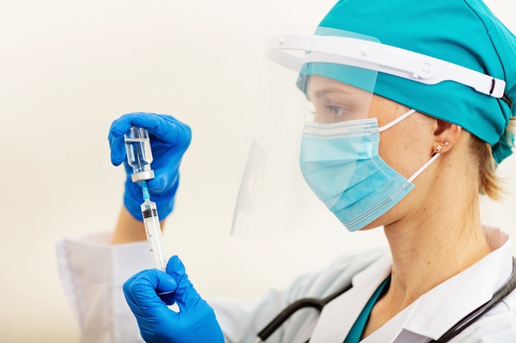 ärztin mit schutzvisier und maske bereitet impfung gegen covid 19 im krankenhaus vor