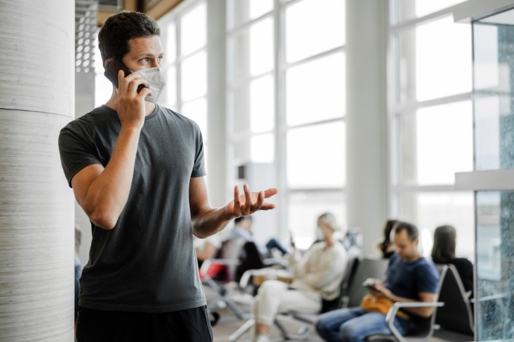 junger mann mit schutzmaske gegen covid 19 wartet auf dem flughafen während der pandemie