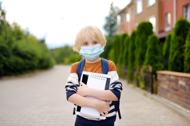 kind mit schutzmaske im freien während der covid 19 pandemie