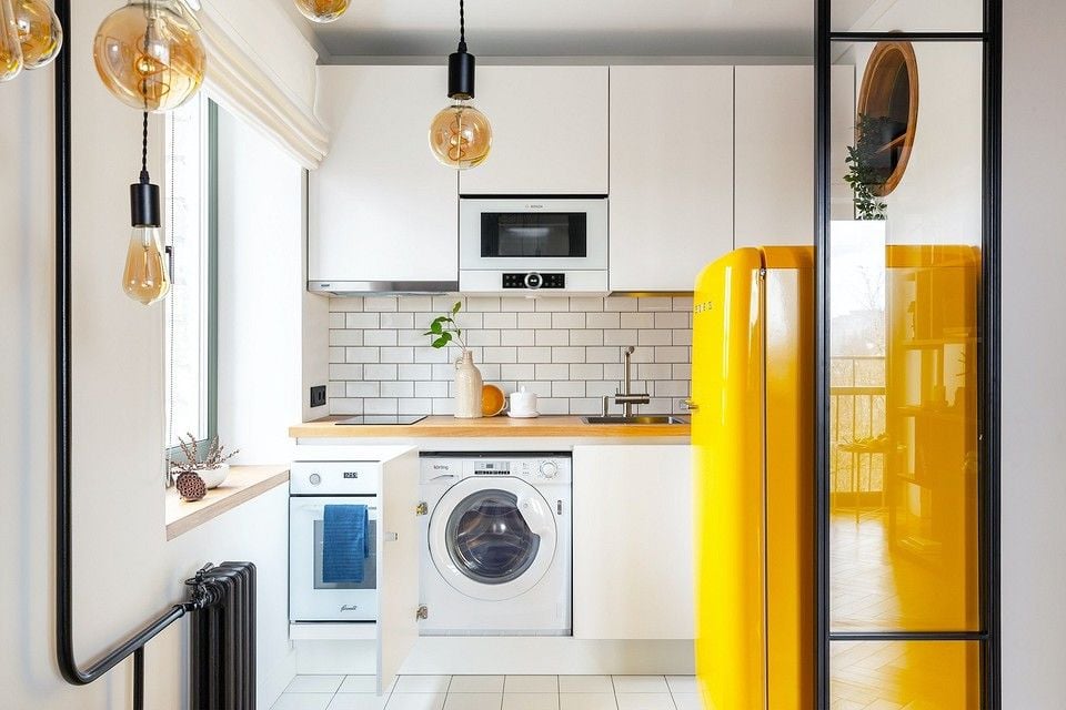 kleine weiße Küche mit Waschmaschine hinter Tür versteckt