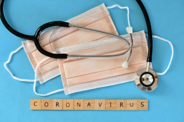 stethoskop und schutzmaske neben aufschrift coronavirus aus holz