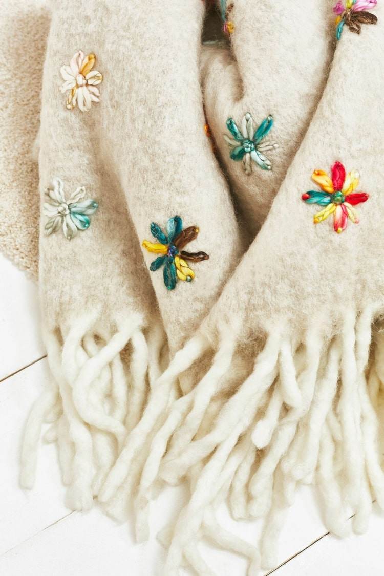 Dezente und Schöne Stickereien aus bunten Blumen auf einer Wolldecke mit Fransen