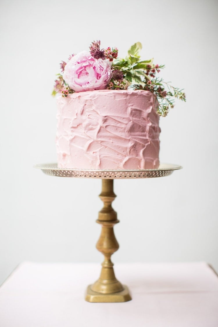 Hübsche Hochzeitstorte in Rosa mit gestrichener Creme auf einem hohen Ständer