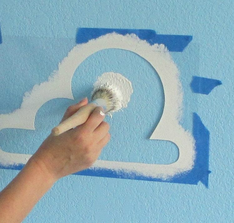 Schablonieren von Wolken mit Stumpfpinsel auf der Wand