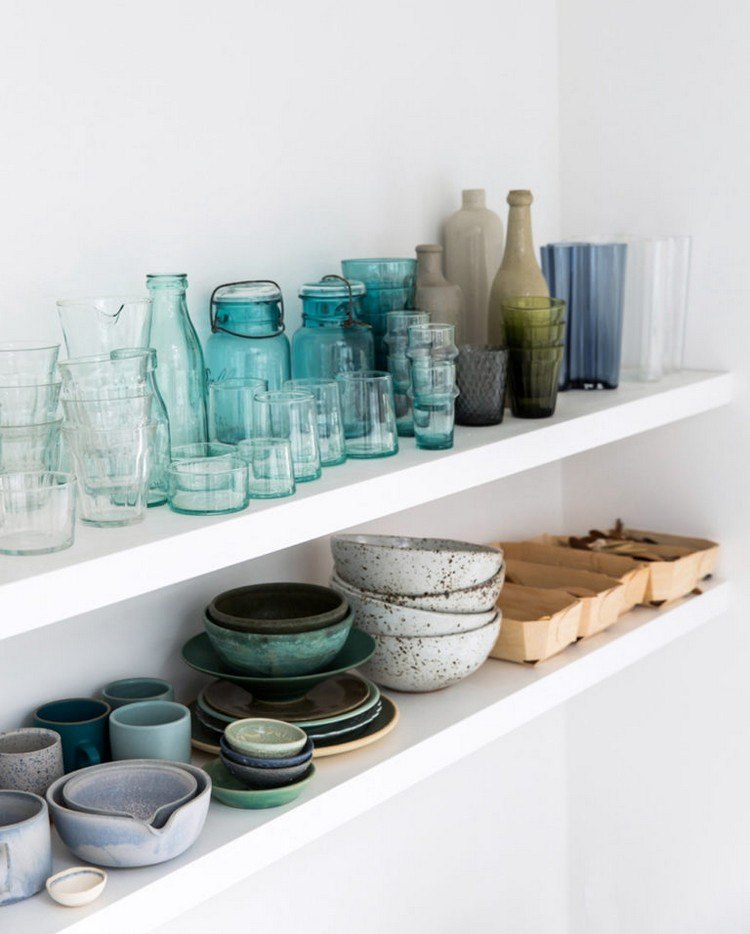 bunte Glasflaschen und Gläser und Feinsteinzeug Keramik auf weißen minimalistischen Küchenregalen