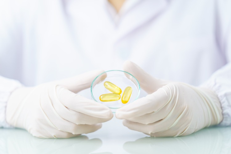 forscher hält ein reagenzglas mit omega 3 fettsäuren in form von kapseln