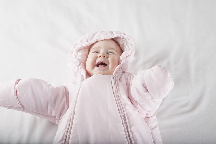 glückliches Baby im rosa Schneeanzug