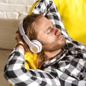 junger mann hört musik zum einschlafen auf der couch