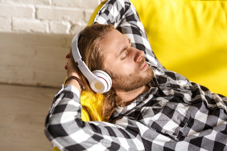junger mann hört musik zum einschlafen auf der couch