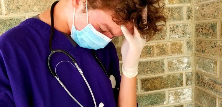 medizinischer mitarbeiter hält sich am kopf in seiner mittagspause während covid 19 pandemie