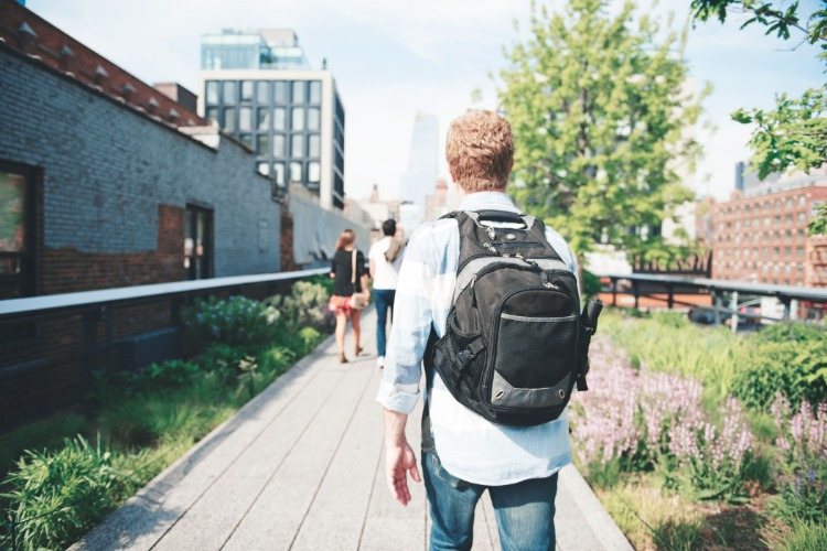 student mit rucksack spaziert im freien neben campus in der stadt