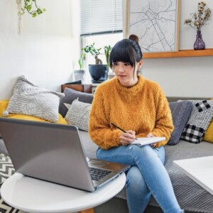 Junge Frau arbeitet im Homeoffice vom Sofa