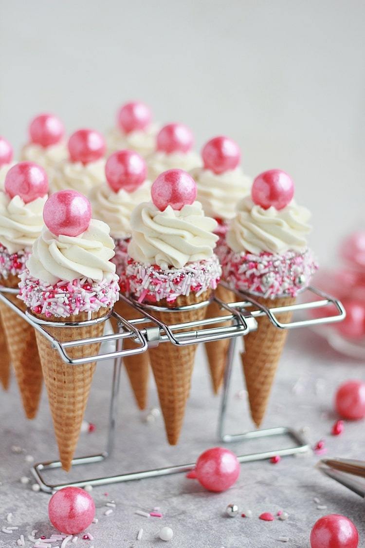 Leckere Muffins in spitzen Eiswaffeln mit rosa Streuseln und essbaren Perlen