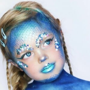 Meerjungfrau schminken für Kinder in blauen Farben und mit Schuppen und Glitzersteinen