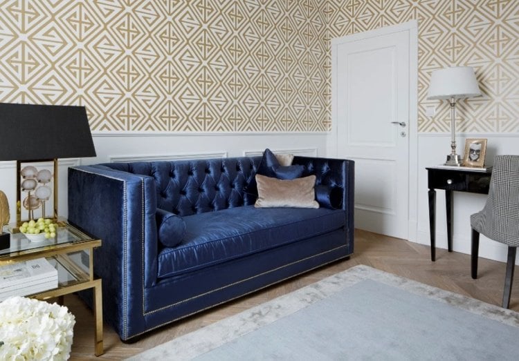 dunkelblaues sofa mit steppungen und goldenen nieten und accessoires