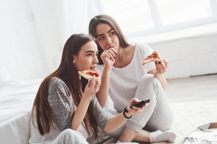 zwei mädchen weisen gestörtes essverhalten beim essen von pizza während fernsehen auf