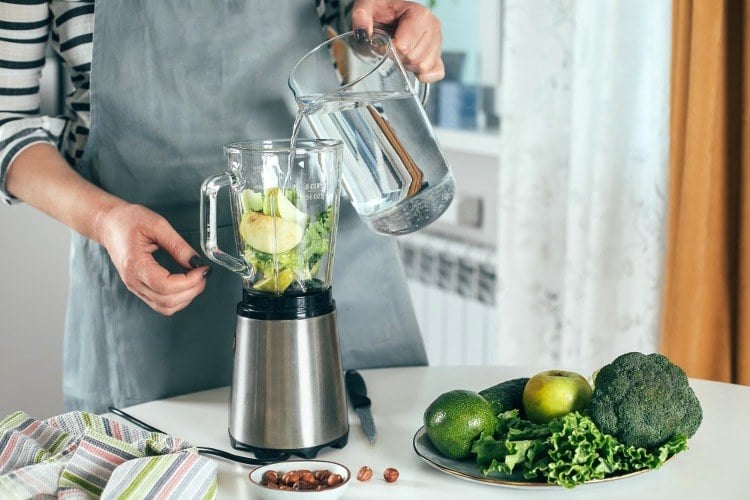 grüner smoothie zubereitung in mixer durch zutaten wie brokkoli sowie äpfel und avocado