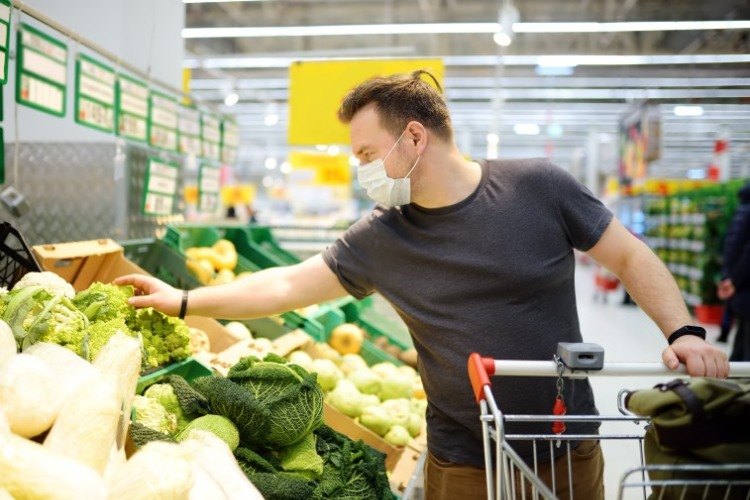 mann mit schutzmaske wählt vegane vollwertkost während der covid 19 pandemie aus