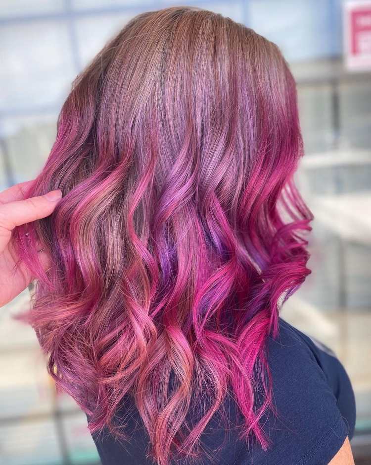 rosa und lila Strähnchen auf braunem Haar wie ein Sonnenuntergang