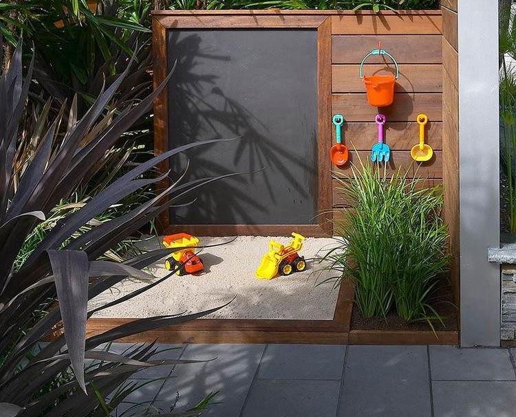 Spielecke für Kinder im Garten mit Kreidetafel und Sandkasten