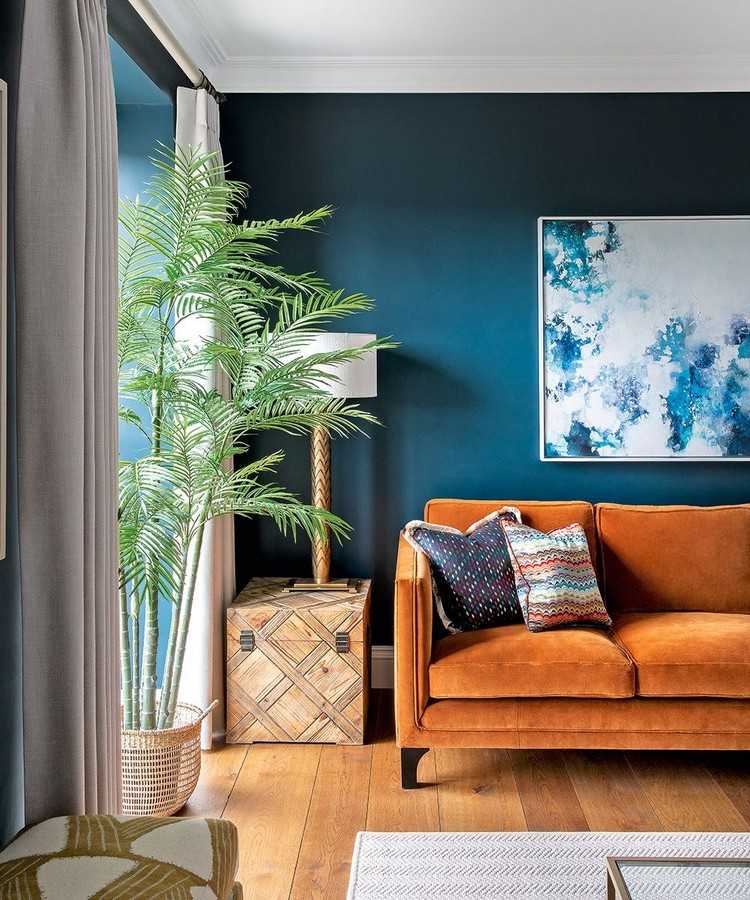 Wohnzimmer Ideen in 2021 dunkelblaue Wand Terrakotta Sofa und grüne Palme in Korb