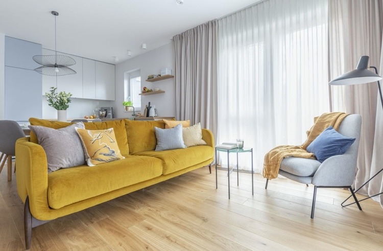 gelbes Sofa als Akzent im hellgrauen Wohnzimmer