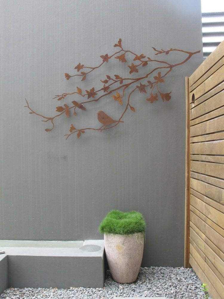 Filigraner Zweig aus Edelrost zum Dekorieren einer grauen Terrassenwand