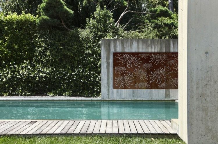 Minimalistische Gartengestaltung am Pool mit Cortenstahl Sichtschutz eingefasst in Sichtbeton