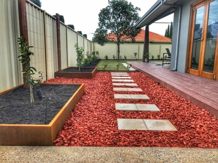 Niedriges Cortenstahl Hochbeet zu rotem Kies im minimalistischen Gartenstil