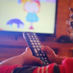 kind mit fernbedienung schaut zeichentrickfilm im fernsehen