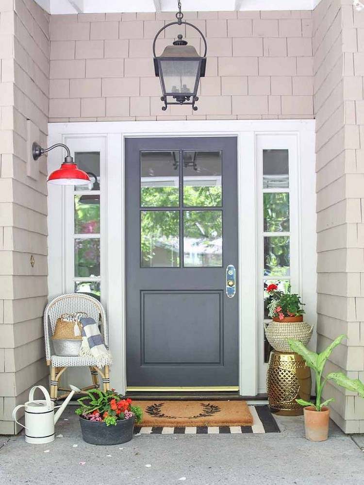 Dekoration vor der Haustür im Sommer mit Pflanzen Korb Gießkanne und Stuhl