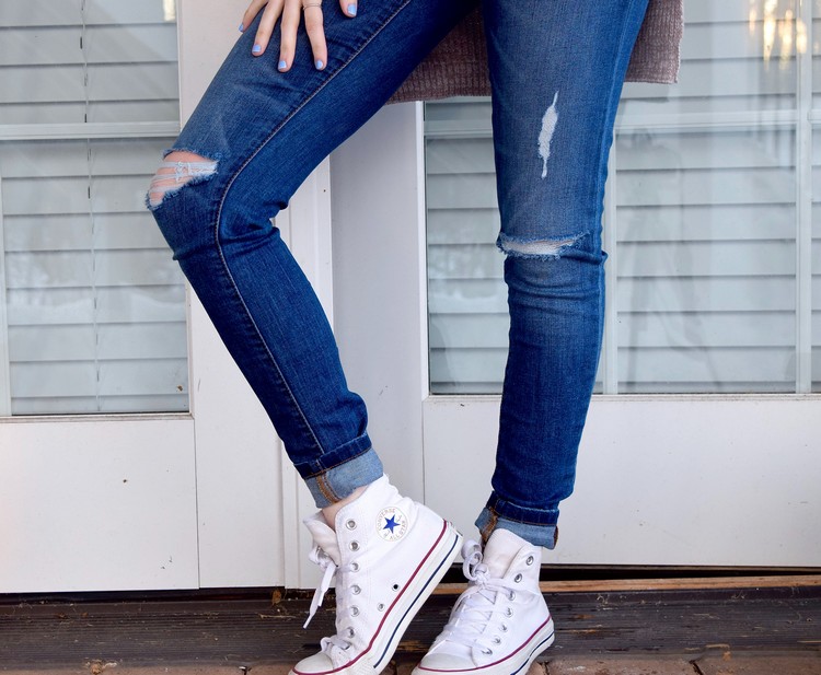 Dunkelblaue Slim Fit Jeans mit weißen Sneakers tragen