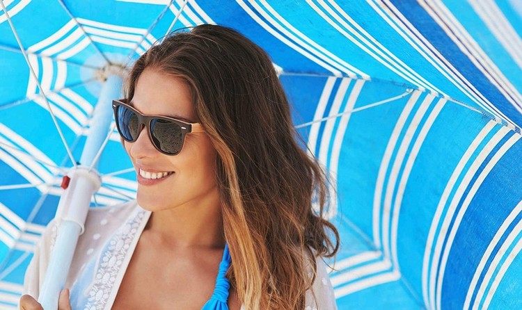 Eine Frau mit Sonnenschirm am Strand im Sommer