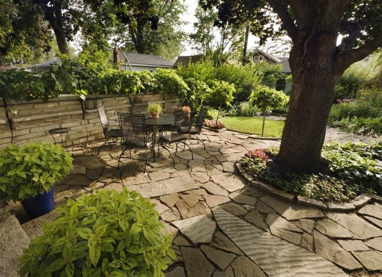 Gartengestaltung unter Bäumen mit Steinterrasse und Bodendeckern