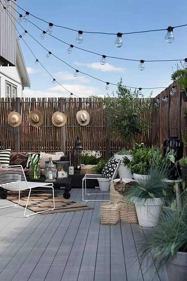 Sommerdeko für Terrasse Strohhüte am Zaun grüne Pflanzen in Kübeln
