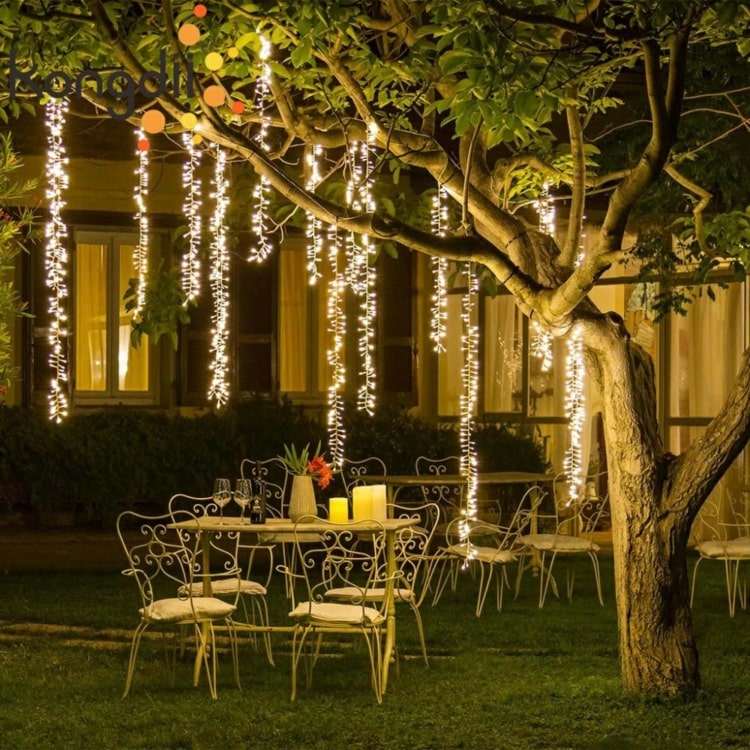 Vertikal hängende Lichterketten an einem Baum für eine romantische Party
